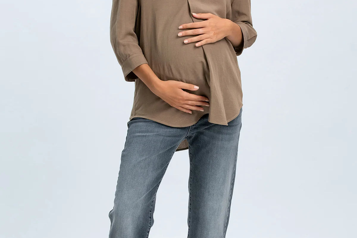 Woman wearing a beige blouse and blue jeans on a white background