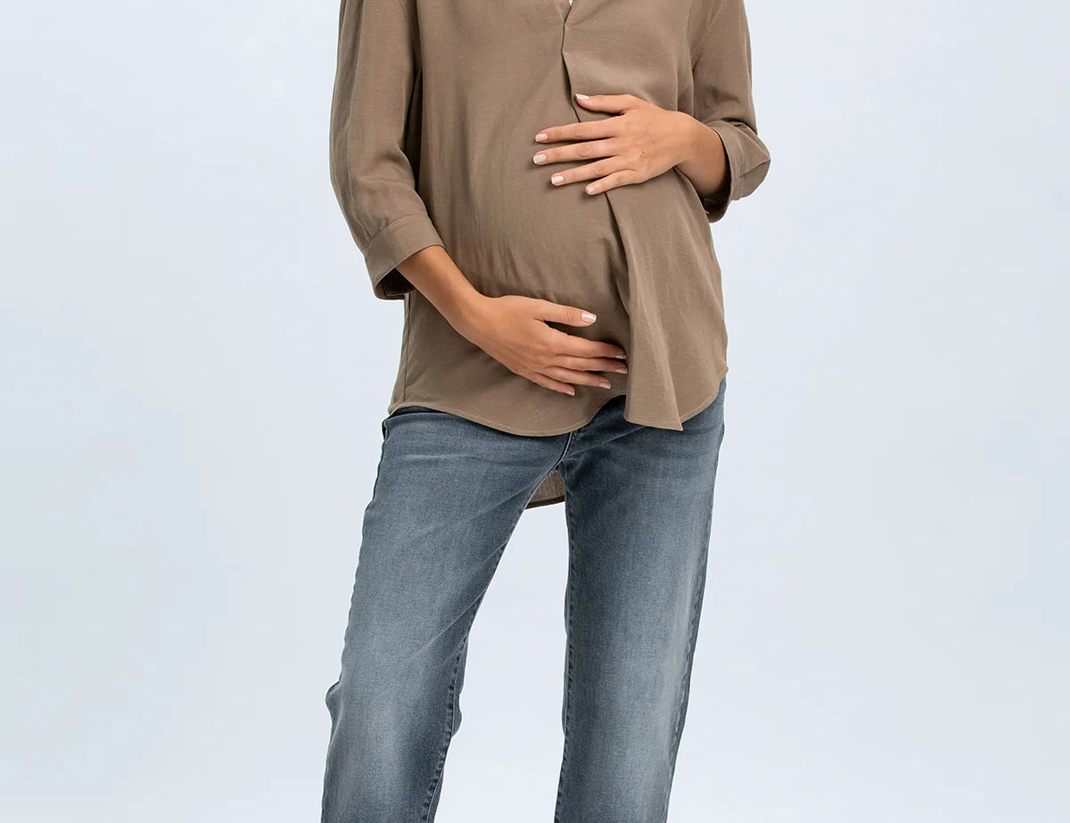 Woman wearing a beige blouse and blue jeans on a white background