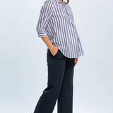 Woman wearing a striped shirt and dark pants on a white background