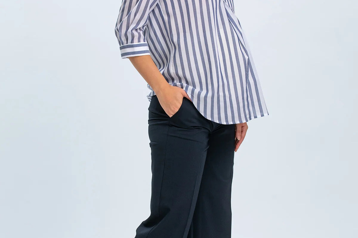 Woman wearing a striped shirt and dark pants on a white background