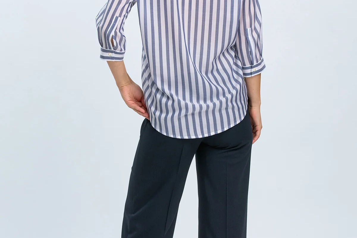 Woman wearing a striped shirt and dark pants on a white background