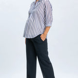 Woman wearing a striped shirt and navy pants on a white background
