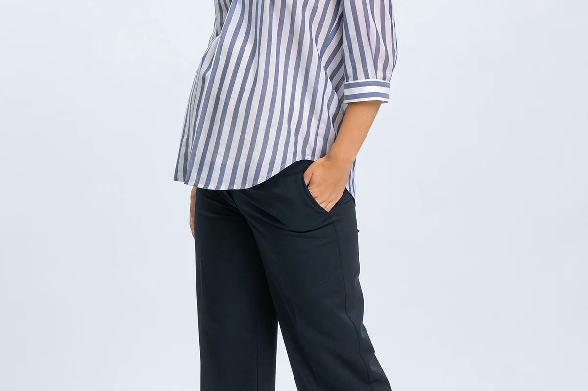 Woman wearing a striped shirt and navy pants on a white background