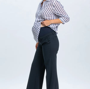 Woman wearing a striped shirt and dark pants on a light gray background