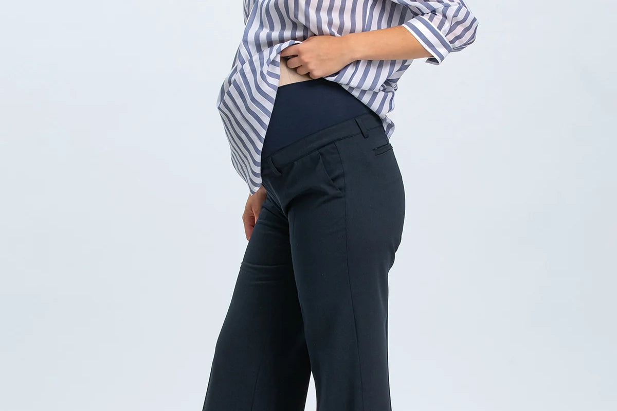 Woman wearing a striped shirt and dark pants on a light gray background