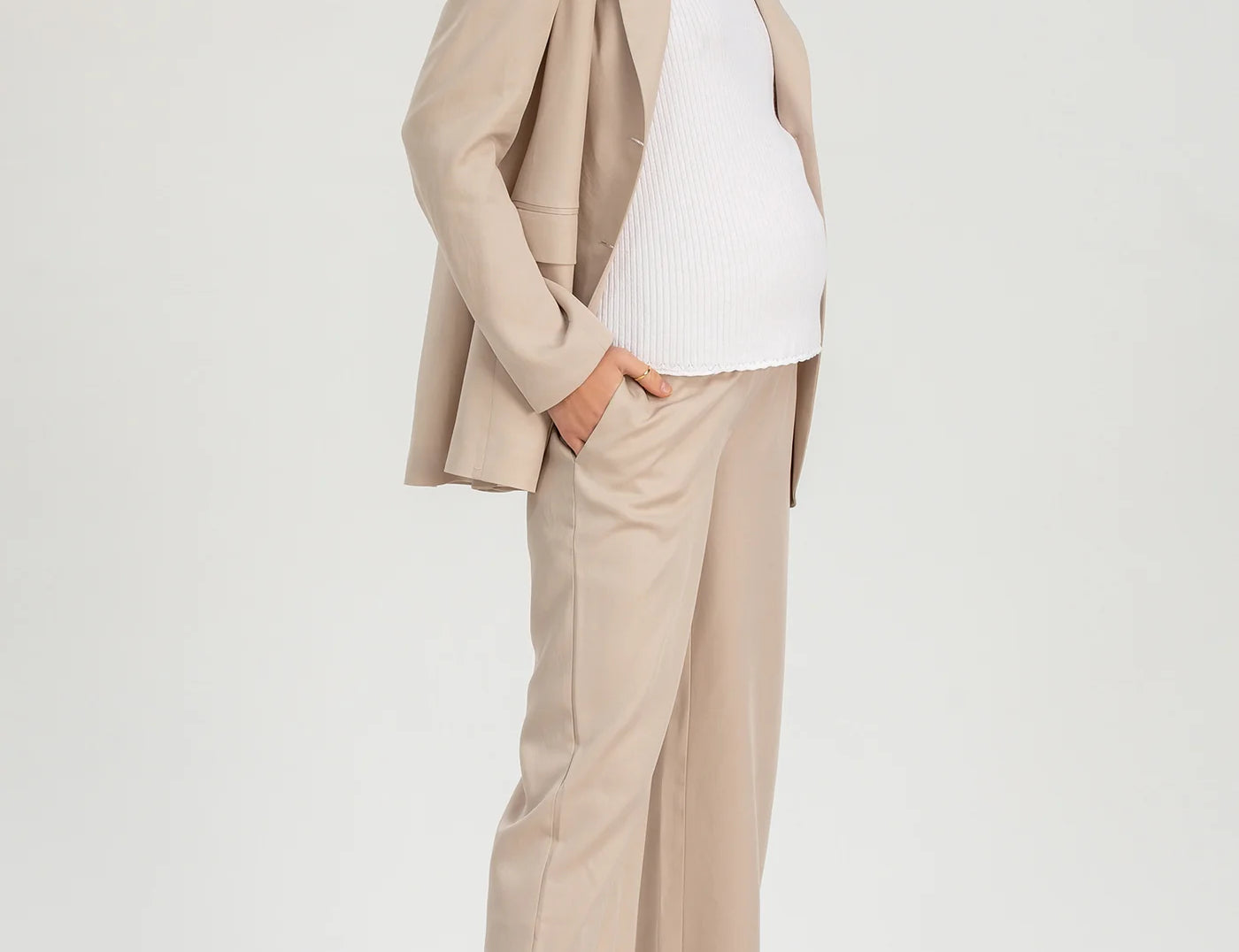 Woman wearing a beige suit with a white top on a light gray background