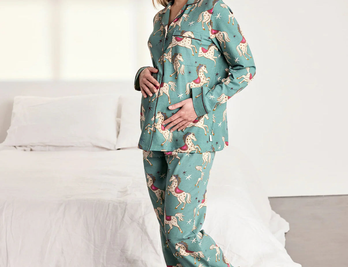 Woman wearing a teal pajama set with a dog pattern in a bedroom.
