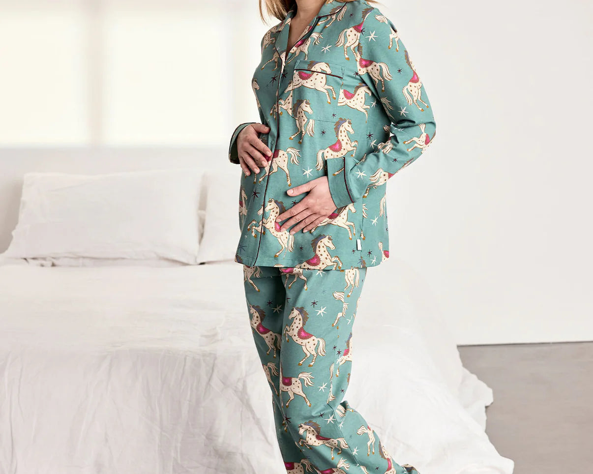 Woman wearing a teal pajama set with a dog pattern in a bedroom.