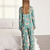 Woman wearing a teal pajama set with animal prints in a bedroom setting.