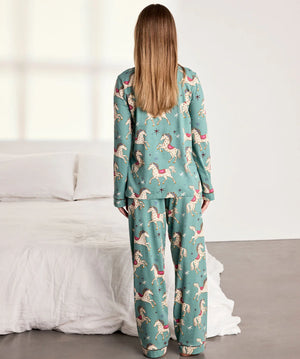 Woman wearing a teal pajama set with animal prints in a bedroom setting.