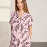 Woman wearing a pink pajama set with leopard print on a neutral background