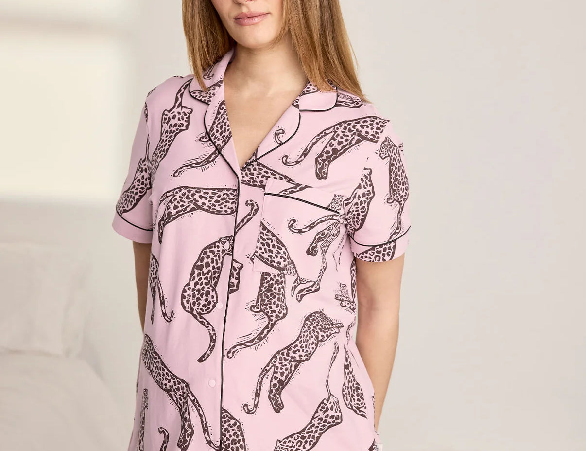 Woman wearing a pink pajama set with leopard print on a neutral background