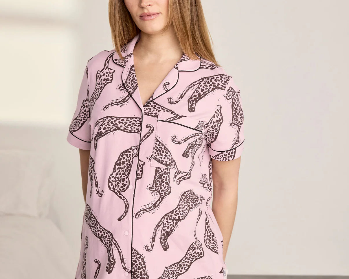 Woman wearing a pink pajama set with leopard print on a neutral background