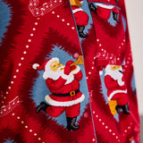 A close-up of a red Christmas-themed button-up shirt featuring a repeating print of Santa Claus playing a trumpet inside blue circular frames, with white musical notes and dots on a red background.