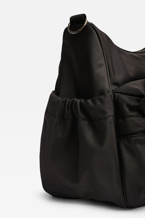 A black nylon hobo bag with a drawstring front pocket and a zippered side pocket, shown on a clean white background.