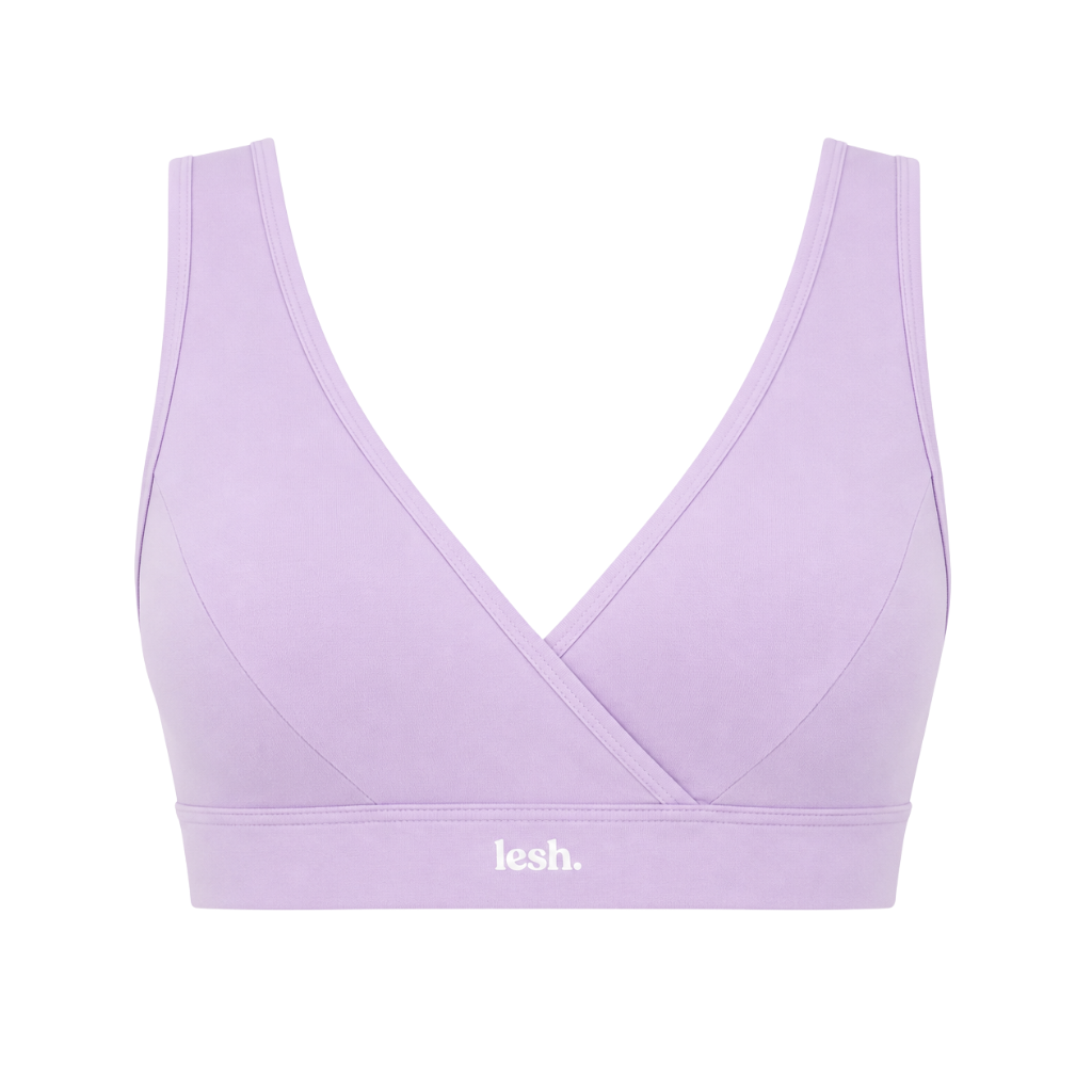 A light purple/lavender sports bra with a crossover wrap front and a wide underband featuring the white 'lesh.' logo, shown against a plain white background.