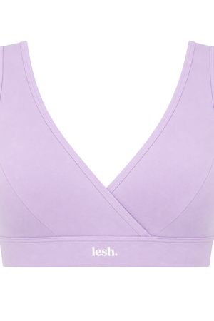 A light purple/lavender sports bra with a crossover wrap front and a wide underband featuring the white 'lesh.' logo, shown against a plain white background.