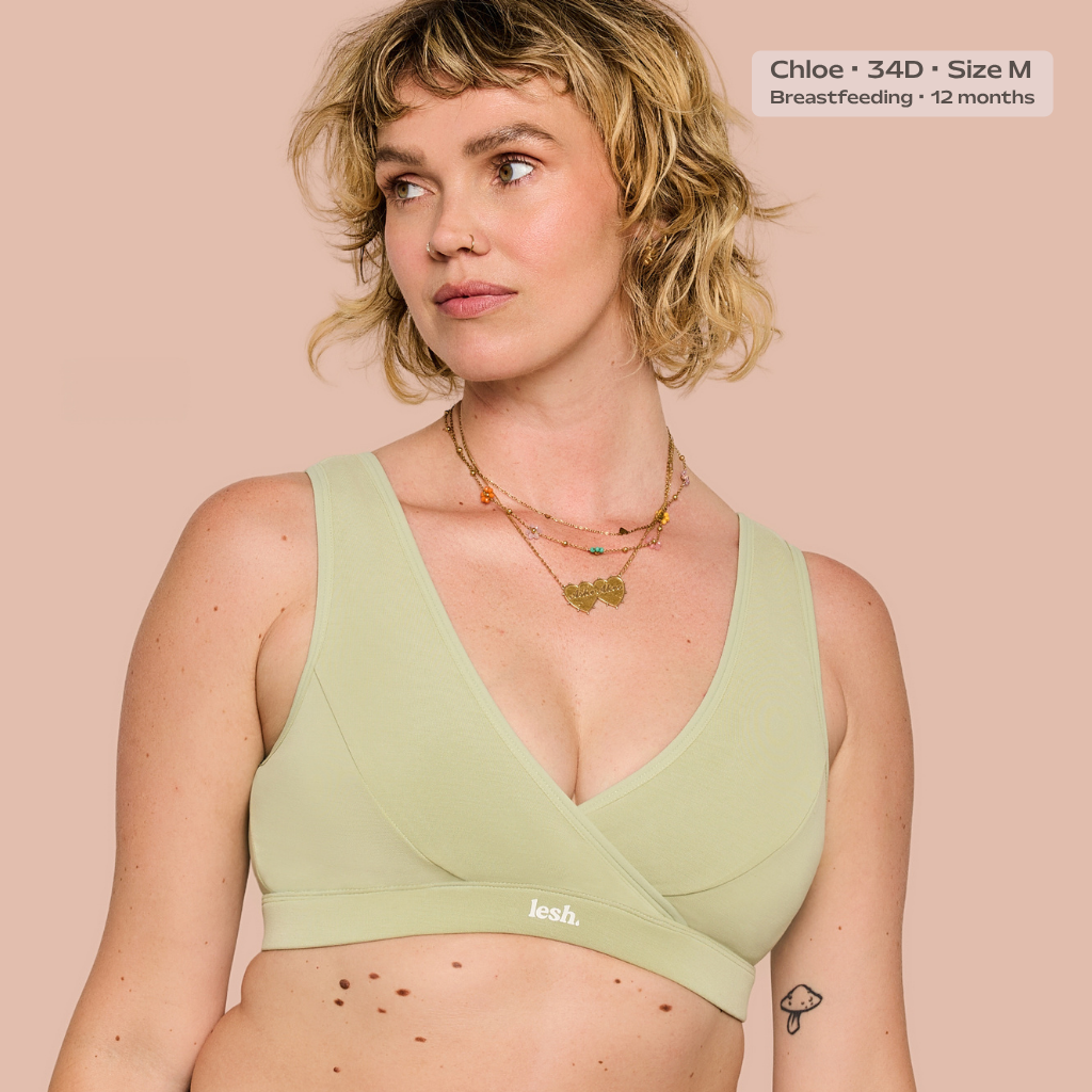 A woman wearing a sage green nursing bra with a crossover front and soft wrap-style cups, shown against a solid pale pink background. Text in the top right reads 'Chloe - 34D - Size M Breastfeeding - 12 months'.