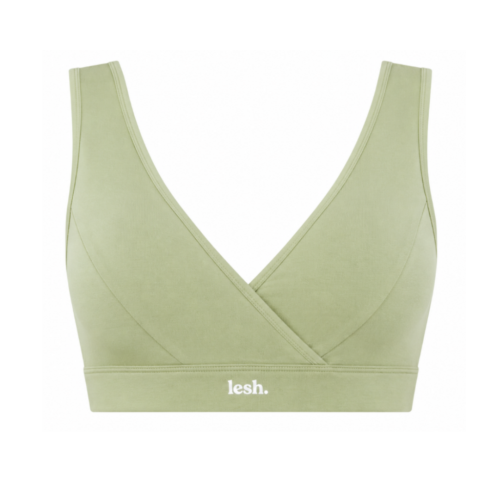 A sage green wireless sports bra with a crossover wrap front and a white 'lesh.' logo printed on the underband, shown against a plain white background.