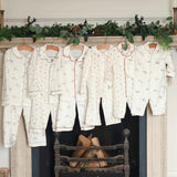 Set of pajama sets hanging on a fireplace mantle with decorative greenery.