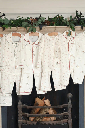 Set of pajama sets hanging on a fireplace mantle with decorative greenery.