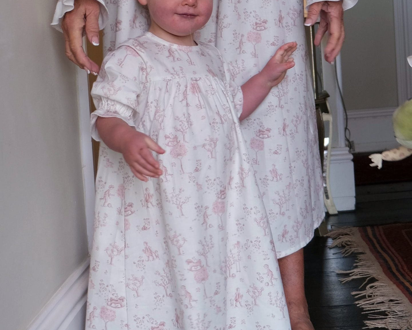 Baby Organic Cotton Nightie, Cordelia Toile: toddler in the pink toile nightie standing in front of an adult in a matching one