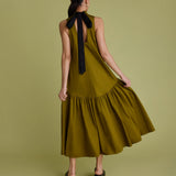 Woman wearing khaki dress with black bow at the back of the neck