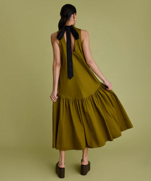 Woman wearing khaki dress with black bow at the back of the neck