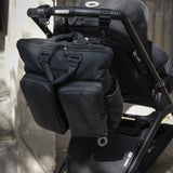 Black stroller with attached bag against a neutral background