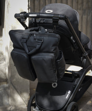 Black stroller with attached bag against a neutral background