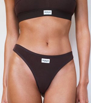 A model wearing a ribbed two-piece bikini set in dark brown, featuring a matching sports bra top and high-cut bikini bottoms with a small white brand label reading 'RENUE'.