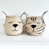 Natural Tiger Belly Basket standing on a white surface next to a matching basket with a sleeping animal face