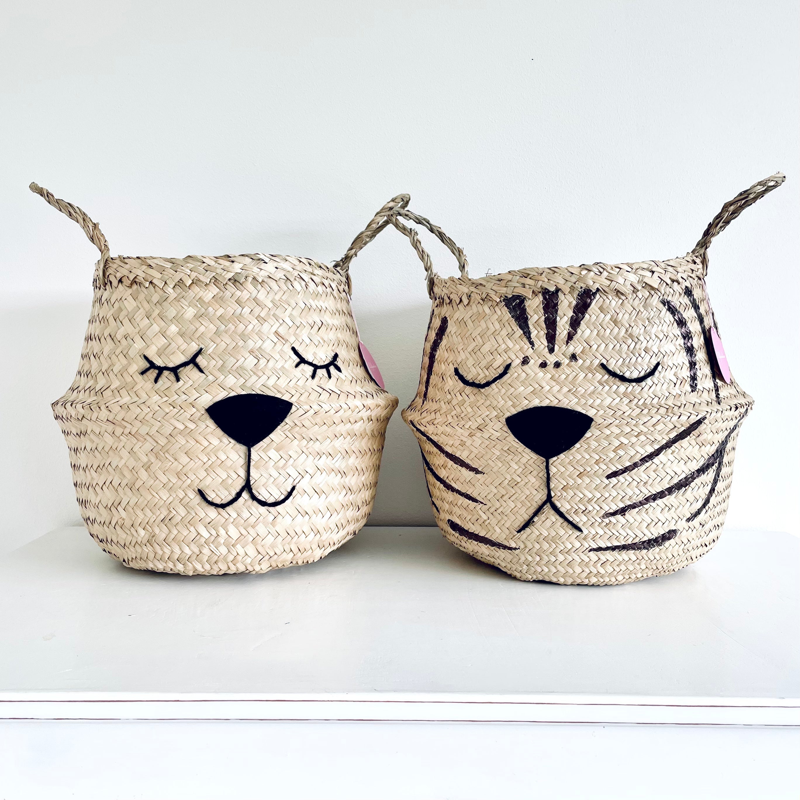 Natural Tiger Belly Basket standing on a white surface next to a matching basket with a sleeping animal face
