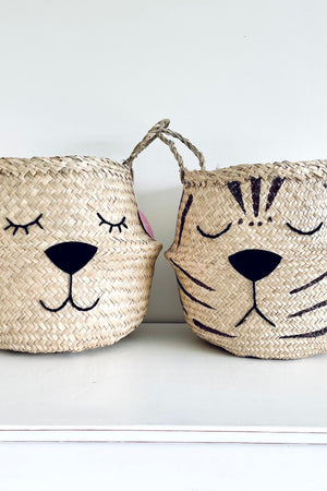 Natural Tiger Belly Basket standing on a white surface next to a matching basket with a sleeping animal face