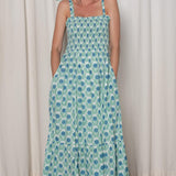 Woman wearing a floral dress standing against a white curtain.