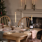 Dining table set for a meal with candles, wine, and Christmas decorations.