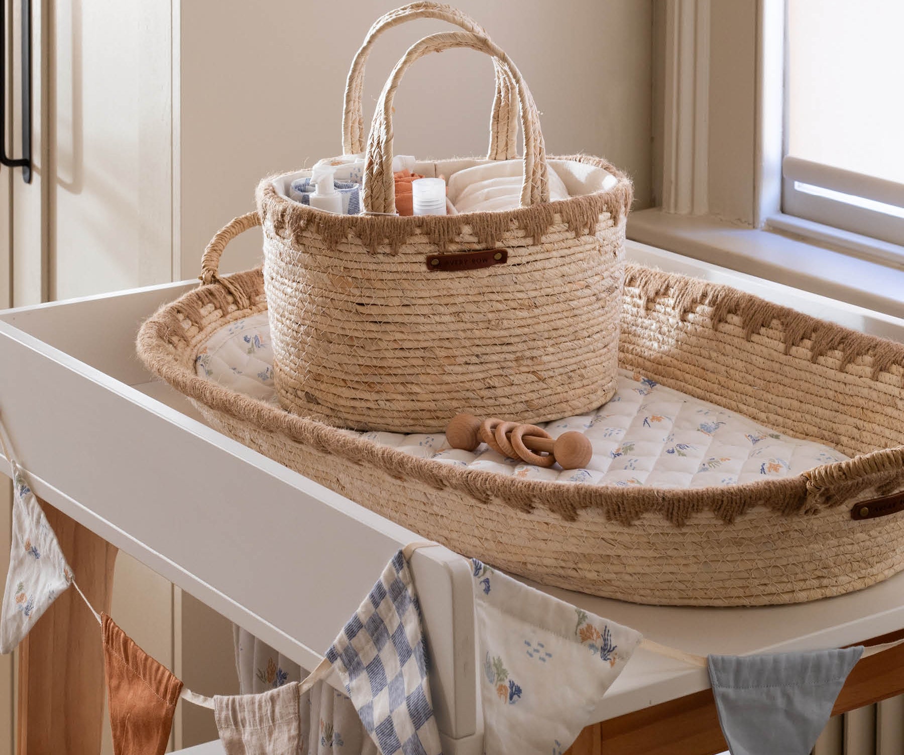 Woven basket and tray on a changing table with baby items in a nursery.