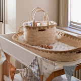 Woven basket and tray on a changing table with baby items in a nursery.
