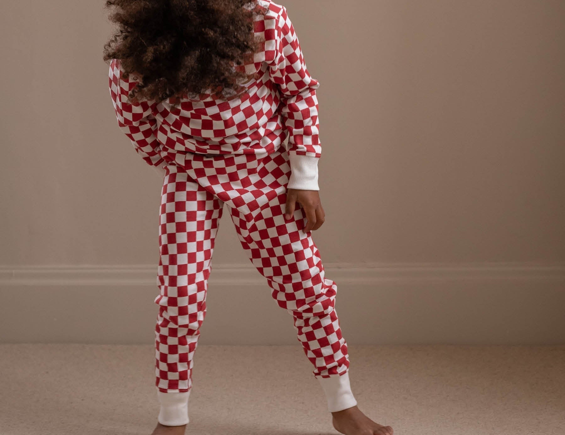Person wearing red and white checkered pajamas against a beige wall.