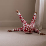 Person wearing red and white checkered pajamas lying on a beige carpeted floor.