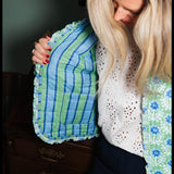Woman wearing a blue and green textured jacket against a neutral background