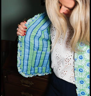 Woman wearing a blue and green textured jacket against a neutral background
