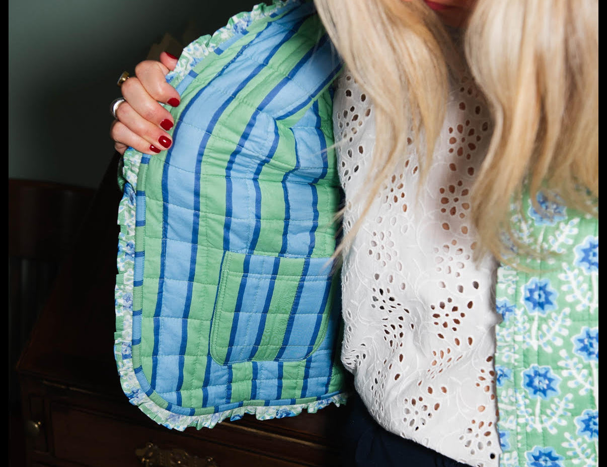 Woman wearing a blue and green textured jacket against a neutral background