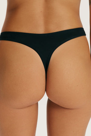 Black thong worn by a person on a plain background