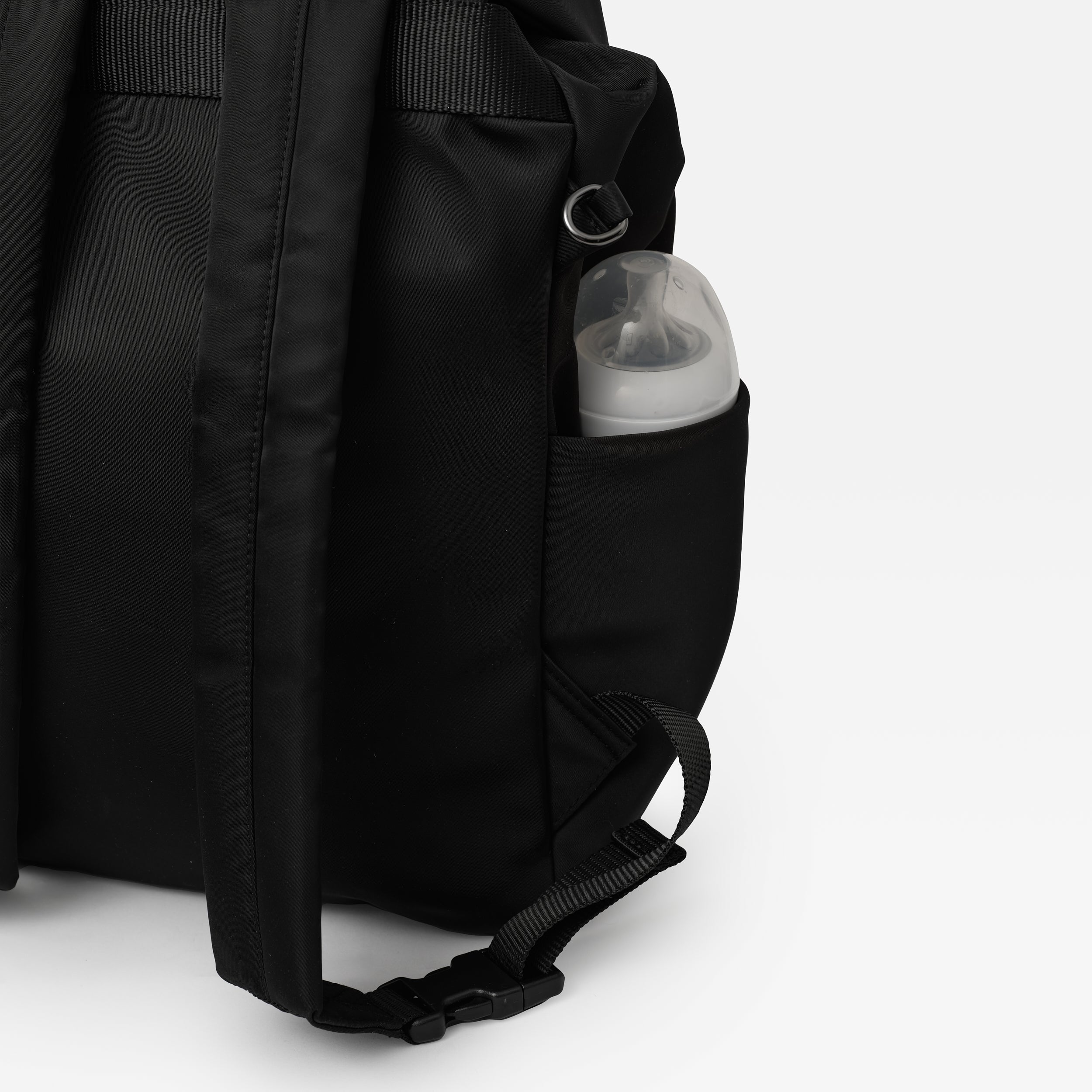 Elise Eco Changing Backpack Black side view with a baby bottle in the side pocket and a D-ring above