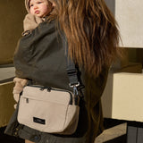 Frida Eco Stroller Organiser Taupe worn crossbody on the back of a woman who is carrying a baby, seen from behind