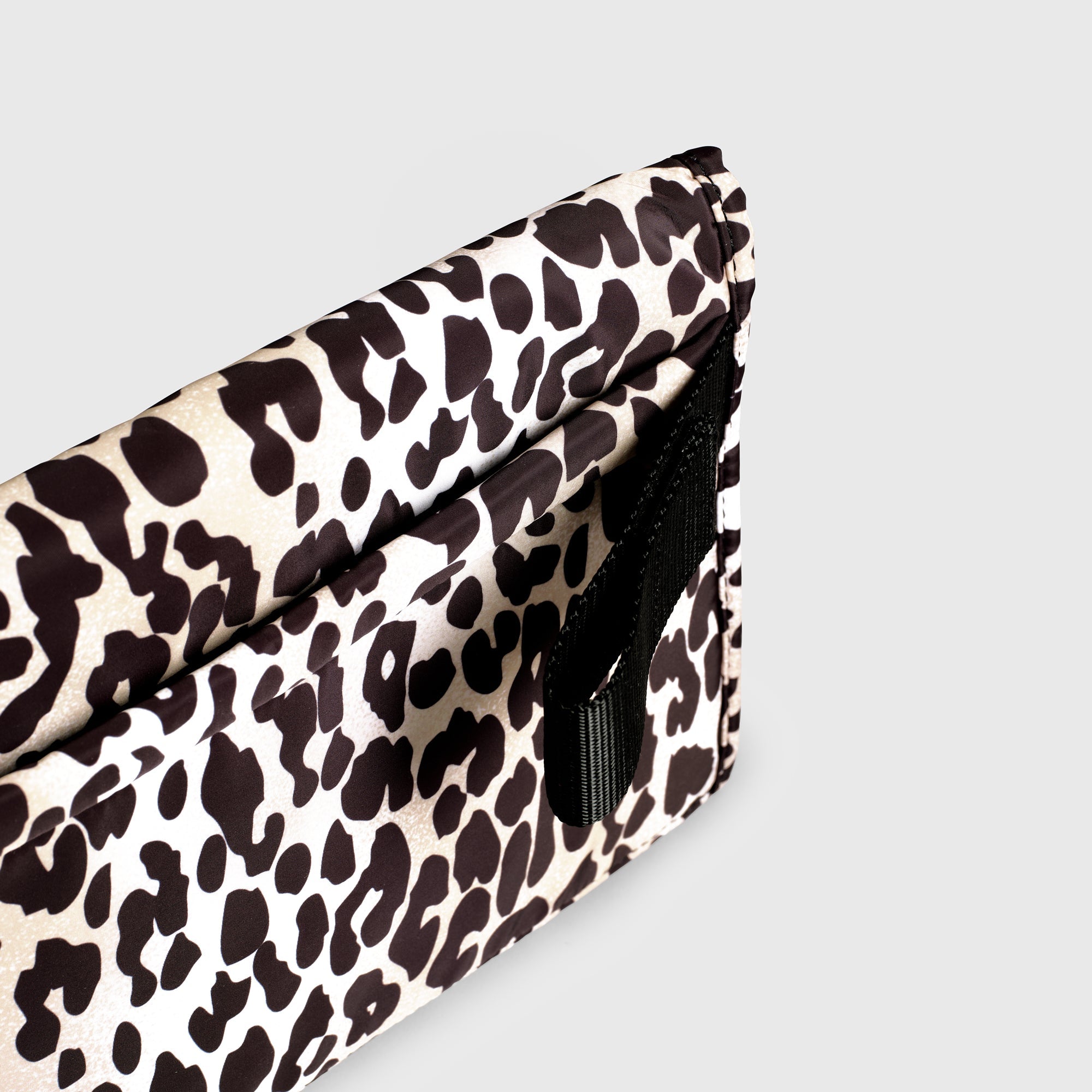 Oslo Eco Travel Changing Mat in Leopard, close-up of the black strap loop on the side of the folded mat