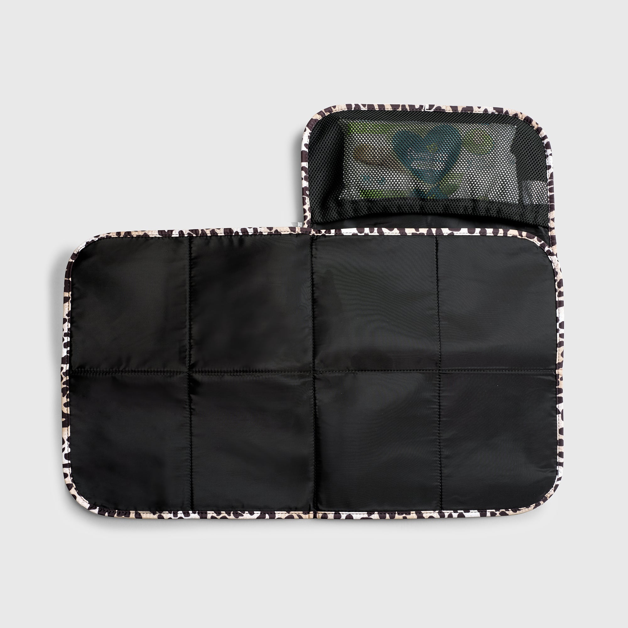 Oslo Eco Travel Changing Mat in Leopard unfolded flat, showing the black quilted mat and a mesh pocket