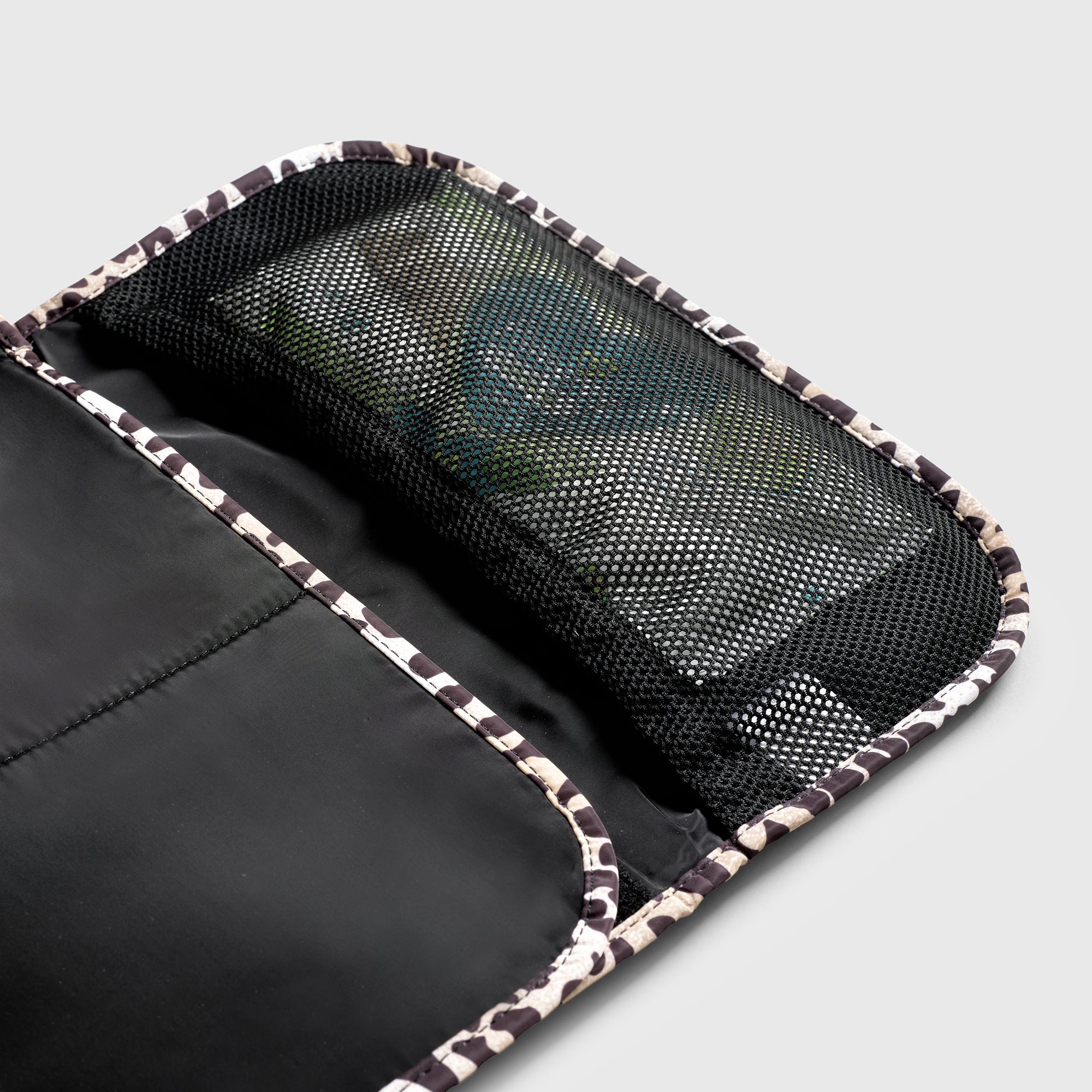 Oslo Eco Travel Changing Mat in Leopard, close-up of the open black mesh pocket with items inside