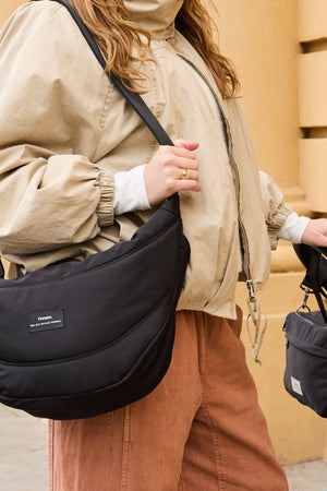Osma Eco Stroller Organiser Black worn across the body by a woman with one hand on a pram handle